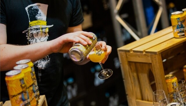 Man schenkt blikje bier leeg in bierglas